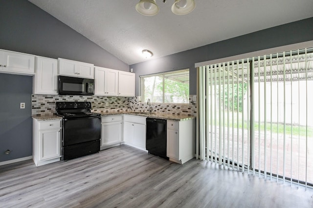 kitchen with a sink, black appliances, white cabinetry, and lofted ceiling