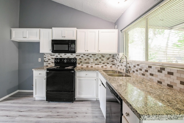 kitchen with a sink, white cabinetry, lofted ceiling, and black appliances