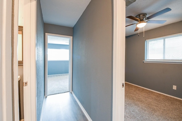 hall featuring baseboards, carpet floors, and visible vents
