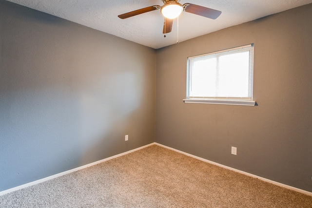 empty room with carpet flooring, a ceiling fan, baseboards, and a textured ceiling