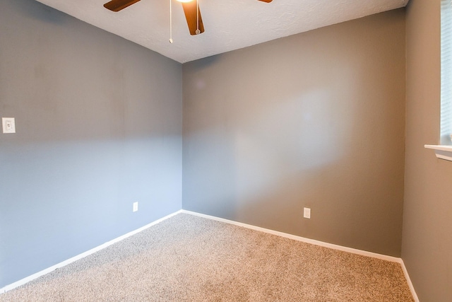 carpeted spare room with a ceiling fan and baseboards