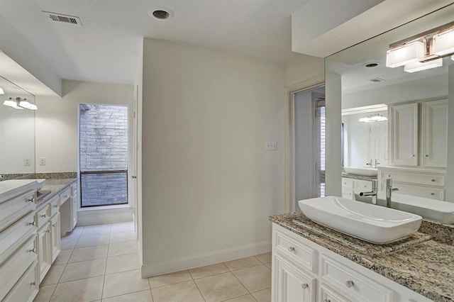 full bathroom featuring baseboards, visible vents, two vanities, and tile patterned flooring