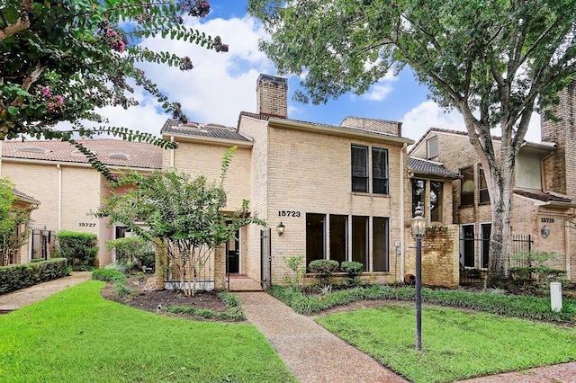 view of front of property with a chimney, brick siding, fence, and a front yard