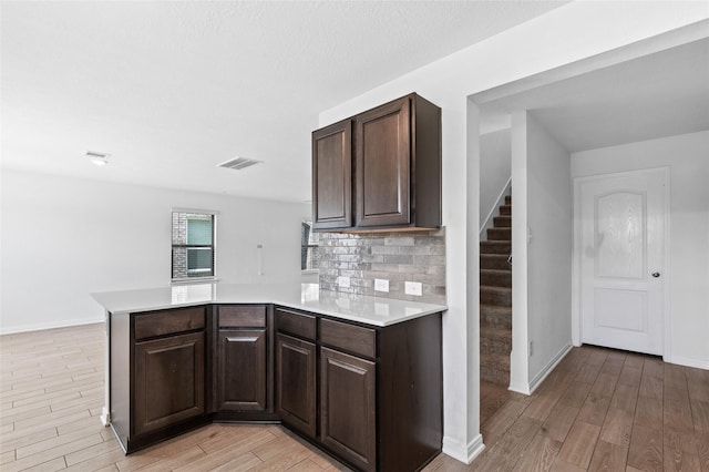 kitchen featuring light wood-type flooring, light countertops, a peninsula, and visible vents
