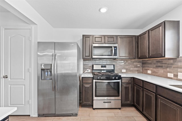 kitchen featuring light countertops, dark brown cabinets, and appliances with stainless steel finishes