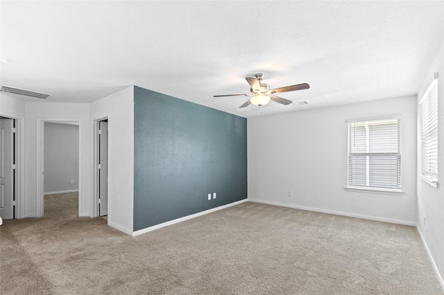 spare room with carpet floors, ceiling fan, baseboards, and visible vents