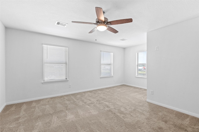 spare room with carpet floors, ceiling fan, baseboards, and visible vents