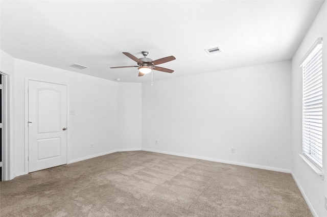 carpeted empty room with visible vents, baseboards, and ceiling fan