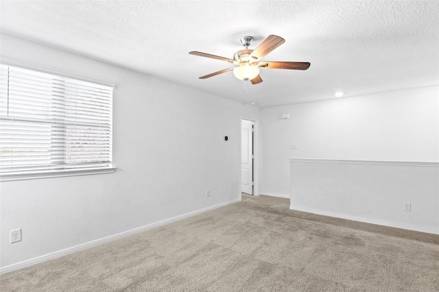 empty room with carpet floors, a ceiling fan, a textured ceiling, and baseboards