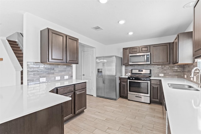 kitchen featuring decorative backsplash, dark brown cabinets, light countertops, a sink, and stainless steel appliances