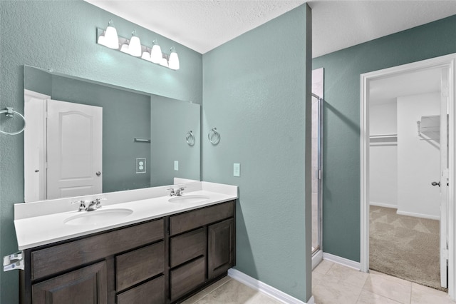 bathroom with a sink, a textured wall, and a stall shower