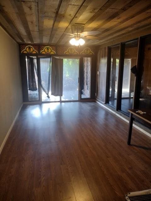 interior space with baseboards, a ceiling fan, and wood finished floors