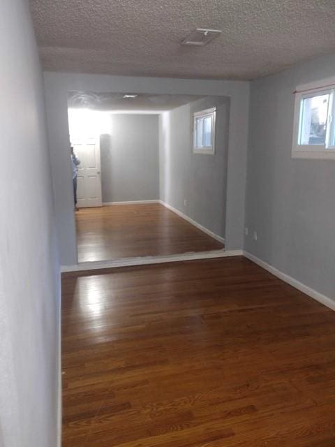 interior space featuring baseboards, a textured ceiling, and wood finished floors