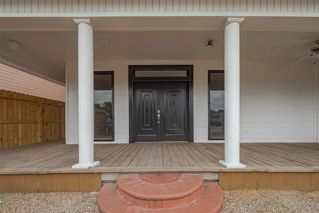 doorway to property with a porch and fence