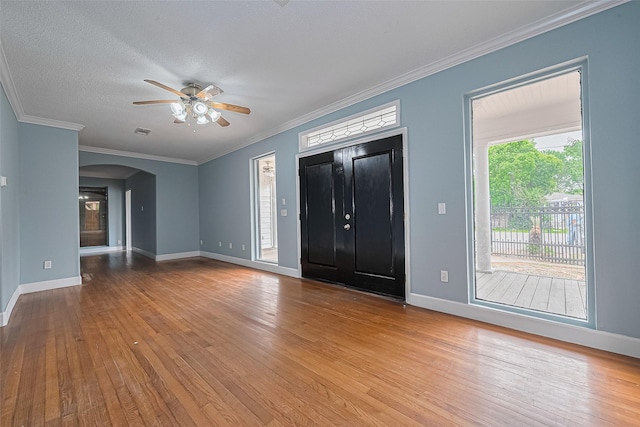 entrance foyer featuring wood-type flooring, a ceiling fan, arched walkways, and baseboards