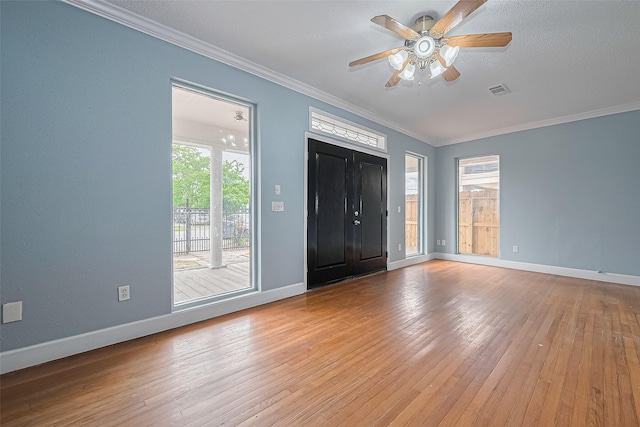 entrance foyer with ceiling fan, visible vents, crown molding, baseboards, and hardwood / wood-style floors