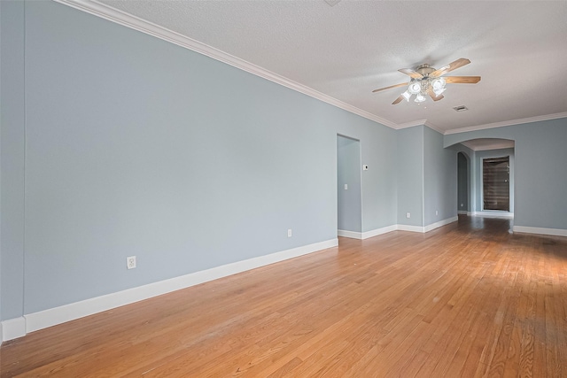 unfurnished room with crown molding, ceiling fan, light wood-style floors, arched walkways, and baseboards