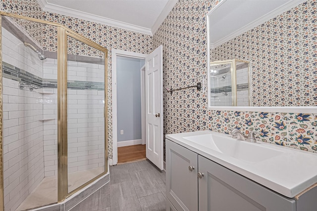 full bathroom featuring wallpapered walls, ornamental molding, vanity, and a shower stall