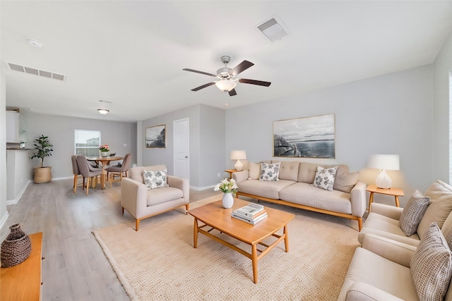 living area with a ceiling fan, baseboards, visible vents, and light wood-type flooring