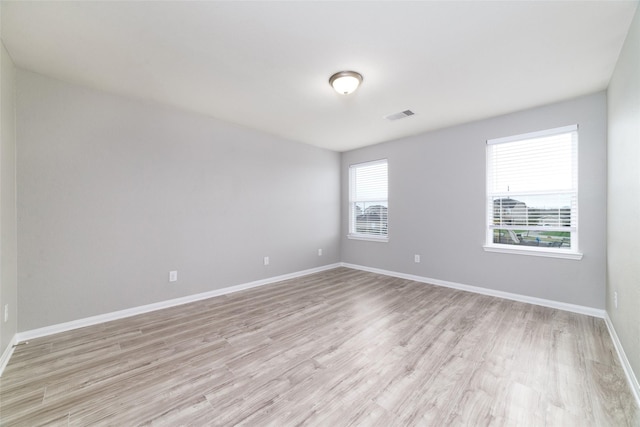 spare room featuring visible vents, light wood-style floors, and baseboards