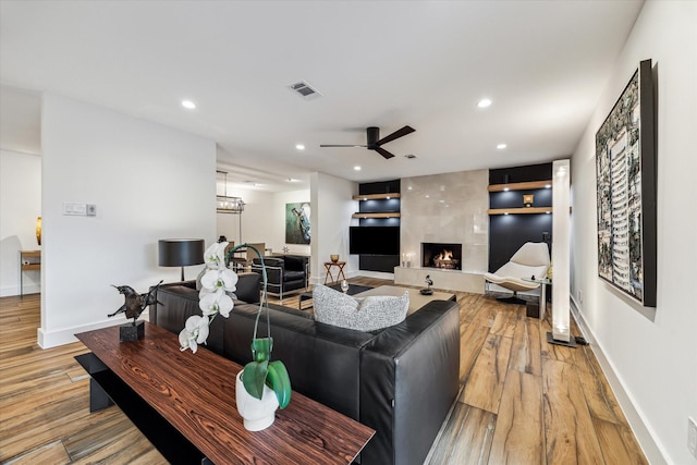 living area with light wood-style floors, a ceiling fan, a premium fireplace, and visible vents