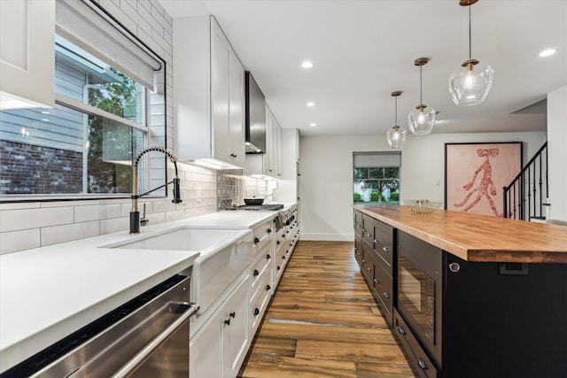 kitchen featuring butcher block countertops, backsplash, appliances with stainless steel finishes, wood finished floors, and white cabinetry