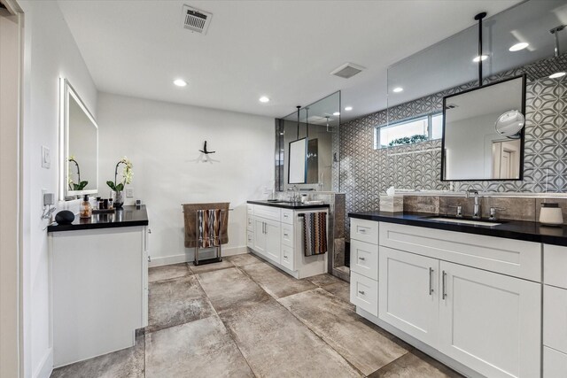 bathroom featuring a sink, tasteful backsplash, two vanities, and visible vents