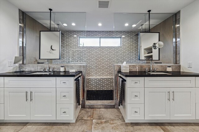 full bathroom with visible vents, a sink, walk in shower, and two vanities