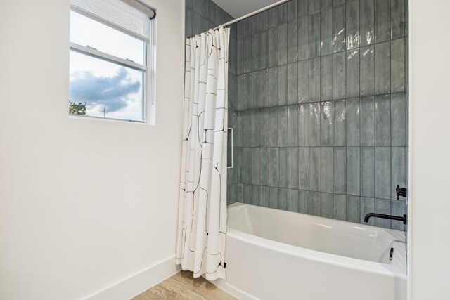 bathroom with baseboards, wood finished floors, and shower / tub combo with curtain