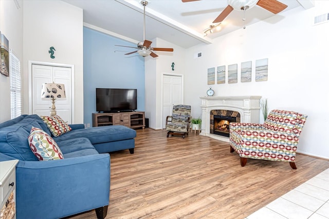 12828 E Madrid, Galveston, TX 77554 - living room featuring visible vents, high vaulted ceiling, a high end fireplace, a ceiling fan, and light wood-style flooring