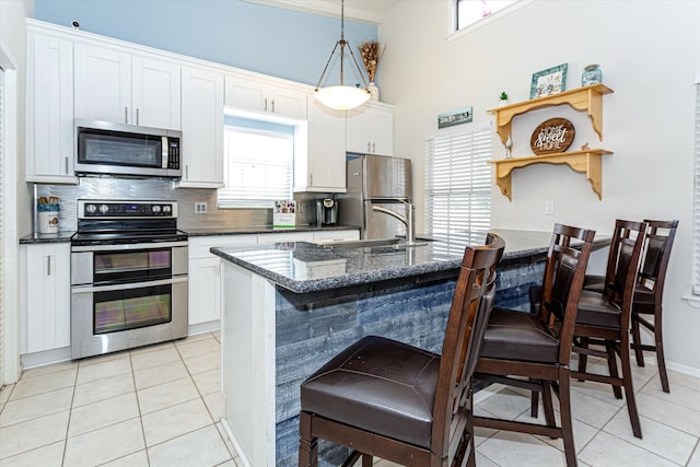 12828 E Madrid, Galveston, TX 77554 - kitchen with white cabinetry, appliances with stainless steel finishes, a kitchen breakfast bar, and tasteful backsplash