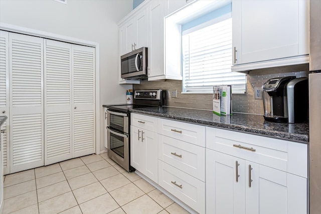 12828 E Madrid, Galveston, TX 77554 - kitchen featuring white cabinets, light tile patterned flooring, dark stone counters, stainless steel appliances, and decorative backsplash