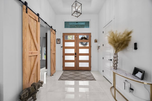 foyer featuring a chandelier, a barn door, and a towering ceiling