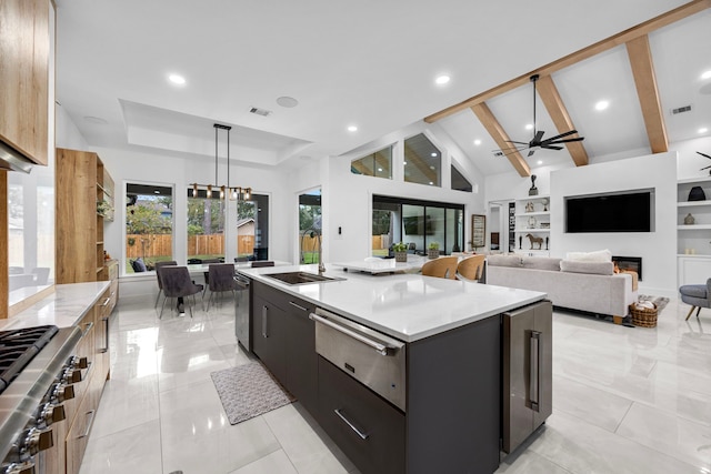 kitchen with visible vents, a glass covered fireplace, a sink, ceiling fan with notable chandelier, and a warming drawer