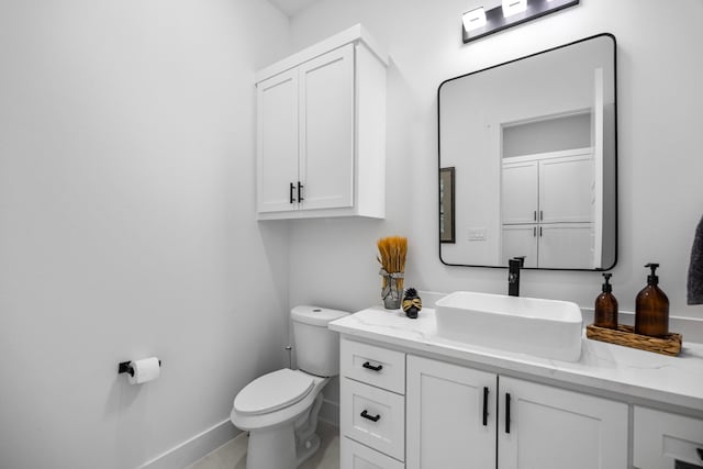 half bathroom featuring baseboards, vanity, and toilet