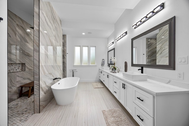full bathroom featuring double vanity, baseboards, a walk in shower, a soaking tub, and a sink