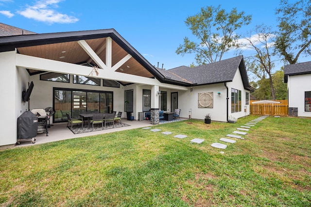 rear view of property featuring outdoor lounge area, fence, a patio, stucco siding, and a yard
