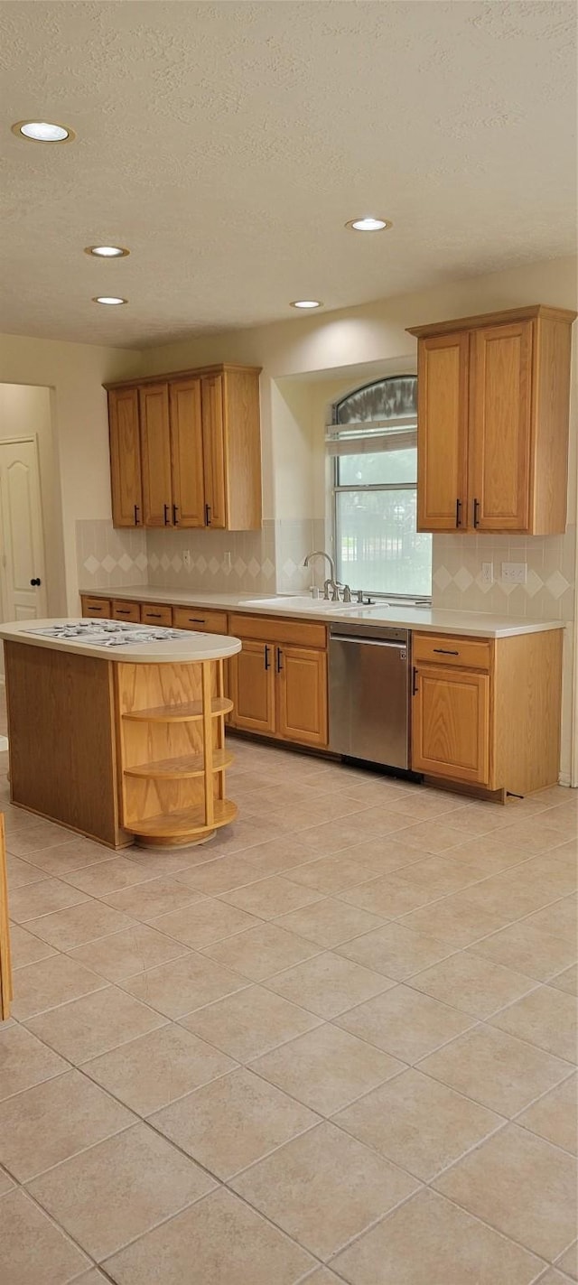 kitchen featuring a sink, dishwasher, light countertops, a textured ceiling, and decorative backsplash