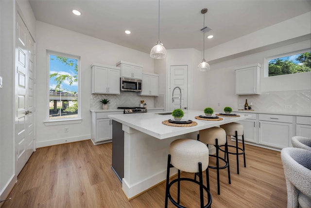 kitchen with stainless steel microwave, light countertops, tasteful backsplash, and a sink