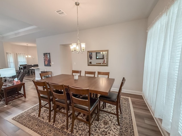 dining room with an inviting chandelier, wood finished floors, and visible vents