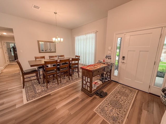 entrance foyer with visible vents, lofted ceiling, baseboards, light wood-style floors, and a chandelier