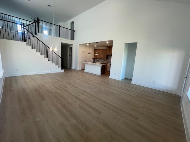 2223 Inglenook Grove Dr, Katy, TX 77493 - unfurnished living room featuring wood finished floors, stairs, and a towering ceiling
