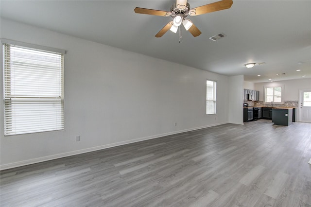 unfurnished living room featuring ceiling fan, baseboards, visible vents, and wood finished floors