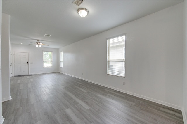 unfurnished room with baseboards, ceiling fan, wood finished floors, and visible vents