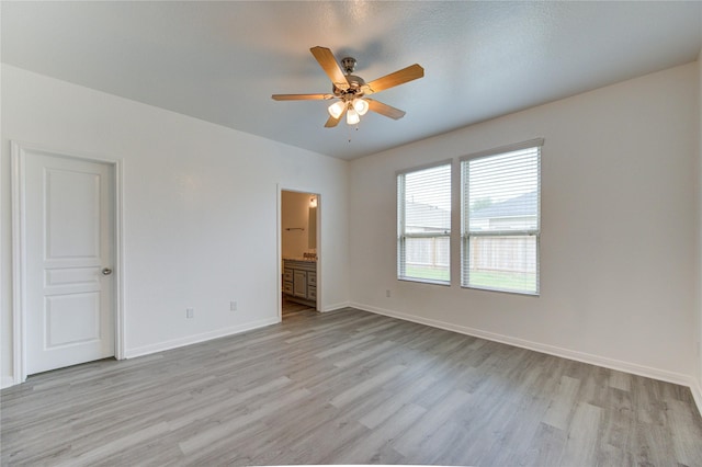 unfurnished bedroom with baseboards, connected bathroom, light wood-style flooring, and ceiling fan