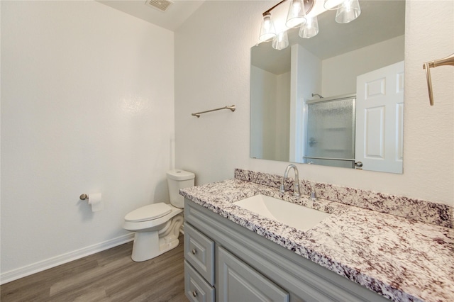 bathroom with visible vents, vanity, wood finished floors, toilet, and a stall shower