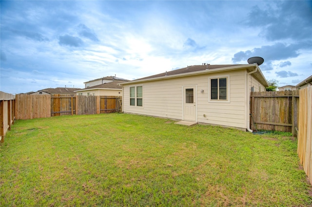 rear view of property with a yard and a fenced backyard
