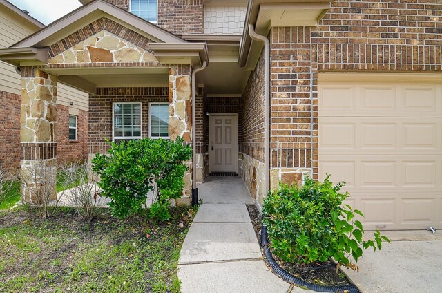 property entrance featuring brick siding, a garage, and stone siding