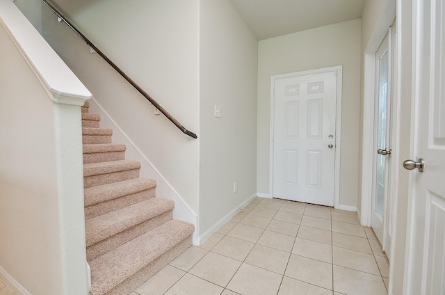 foyer featuring light tile patterned floors, baseboards, and stairs