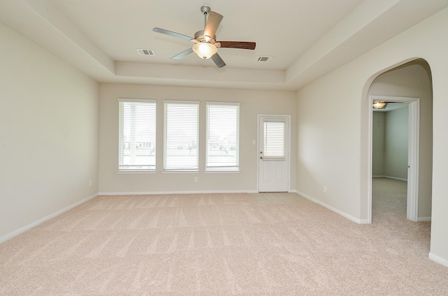 spare room with arched walkways, ceiling fan, light colored carpet, and visible vents